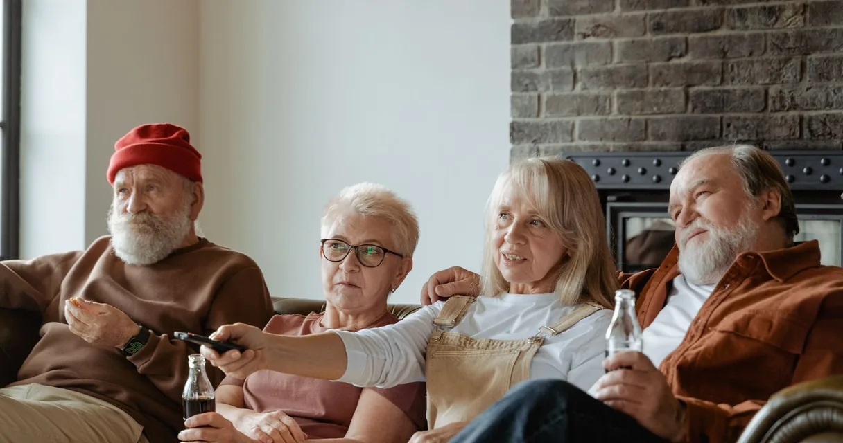 Grupo de idosos assistindo à televisão na sala, ilustrando a smart TV para idosos